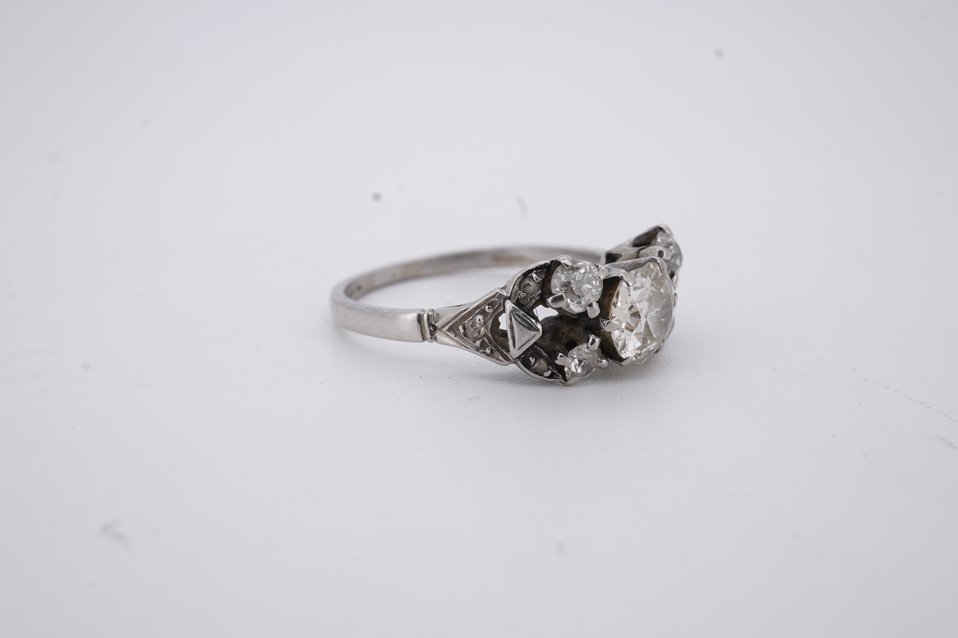 A white metal (stamped platin) and single stone diamond ring, flanked by four smaller diamonds and rose cut diamond chip set shoulders, size P, gross weight 3.8 grams.